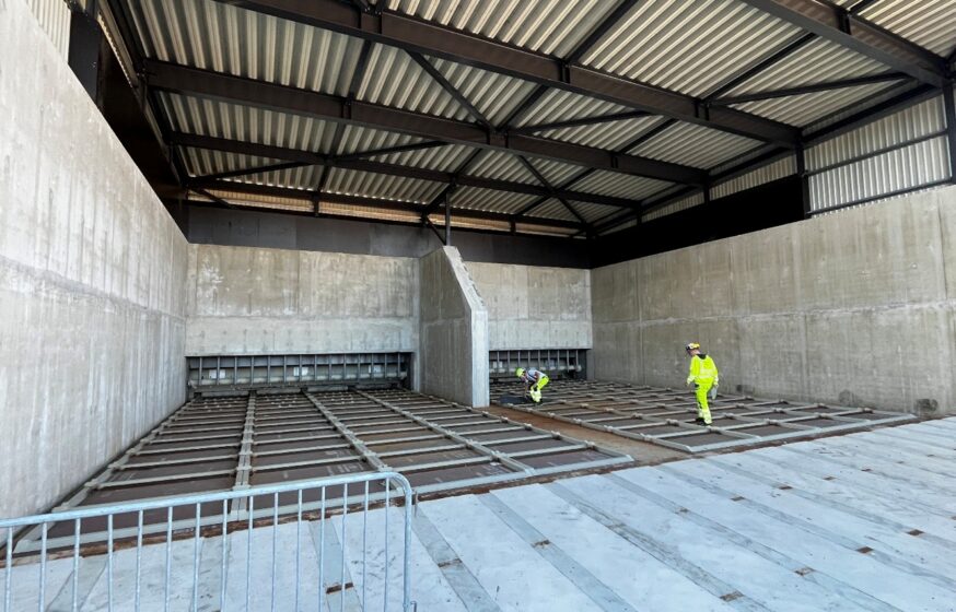 Biomass fuel storage with scraper conveyor system.