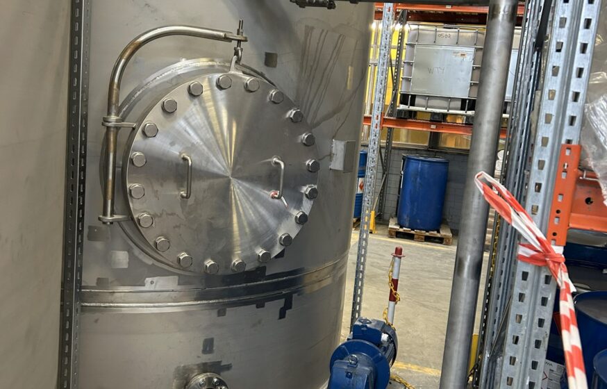 Stainless steel storage tank installation with pump and piping